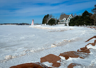 A lighthouse on the edge of the frozen water in winter. 