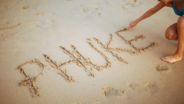 A Female Tourist Writing PHUKET In The Sand. Thailand Beach, Travel, Vacation Memories.
