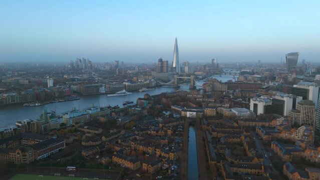A sweeping drone view of the London skyline featuring The Shard and a wide Thames River, Tower of London under a clear sky in the soft light of early morning. London, UK 