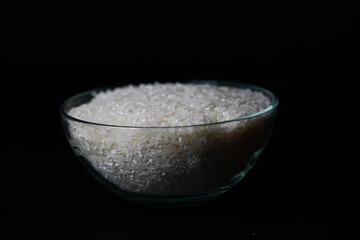 uncooked rice in a bowl isolated on a black background, copy space.