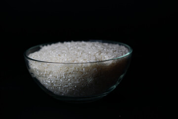 uncooked rice in a bowl isolated on a black background, copy space.