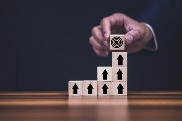 Businessman put wooden step bottom up to target concept business step to target success.