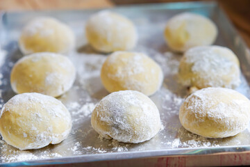 Small balls of fresh uncooked homemade donuts on a wooden table