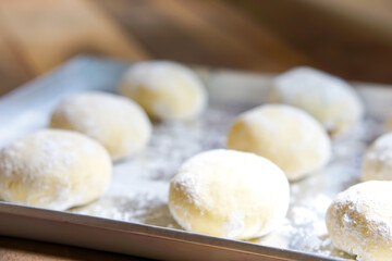 Small balls of fresh uncooked homemade donuts on a wooden table