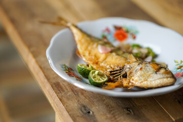 Ikan Peda  or ikan asin fried with sliced chili peppers, onions, and lime, served on a white plate.