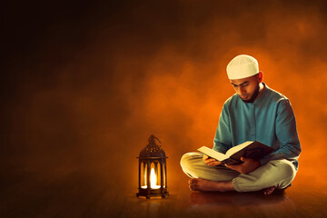 Young asian muslim man with beard reading holy book quran in the mosque at dark night - 739687355
