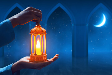 Hands of young asian muslim man holding shiny arabic lantern in the mosque door arch at beautiful blue night sky with stars and crescent moon - 739690371