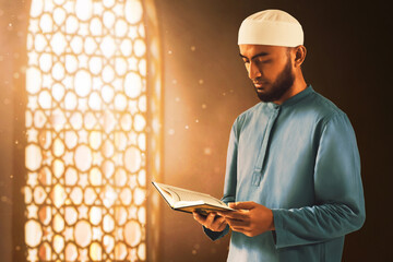 Young asian muslim man with beard reading holy book quran in the mosque window arch