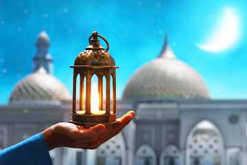 Hands of young asian muslim man holding shiny arabic lantern at blue night sky with stars and crescent moon - 739691730