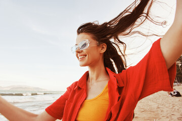Smiling woman with colourful sunglasses enjoying the freedom of a trendy lifestyle at the beach...