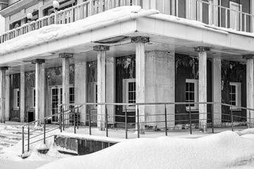 The facade and porch of an old building with columns covered with snow. Black and white.
