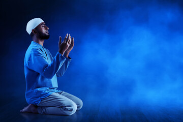 Young asian muslim man with beard praying on dark blue background - 739695597