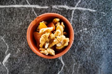 walnut and dried peach fruit on in a small bowl on tiles background 