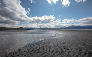 Mud flats at low tide under cumulus clouds on Homer Spit in Homer Alaska United States