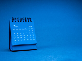 The March 2024, blue small spiral desk calendar for organizer to plan and reminder isolated on blue...