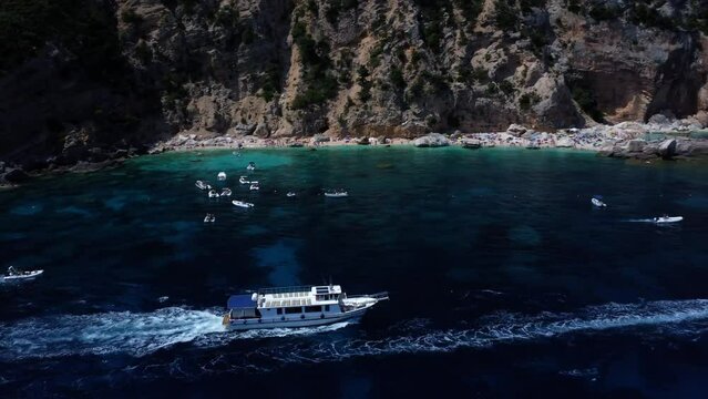 Tourist boat unveiling an overcrowded beach in sardinia. overpopulation