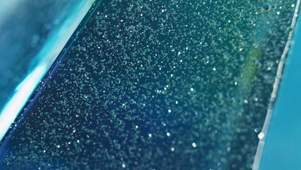 Glitter gel drip. Bubble fluid. Defocused blue purple color sparkling fizzy droplet texture oil paint spill wave motion abstract art background.