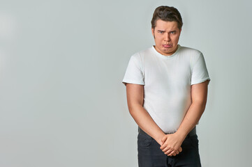 A sad young man stands on a gray background