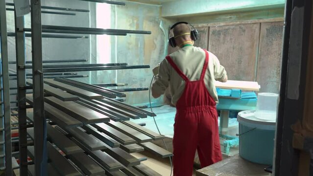 Factory worker paints wooden furniture with a spray gun. Spraying paint on furniture parts in furniture manufacturing