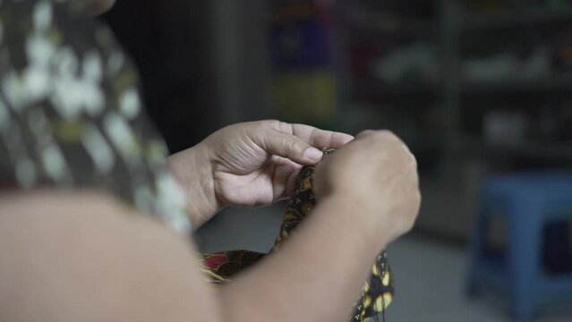 Selective focus of woman hands sewing batik traditional fabric textile