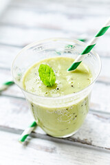 Green smoothie topped with chia seeds on bright wooden background. Close up.