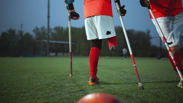 Legs of disabled football plaer with ball and crutches