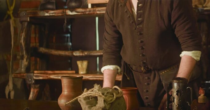 Innkeeper shrugs while knight drinks in tavern closeup. Medieval barkeeper serves alcohol drink to travelling warrior at inn. Hotel owner with guest