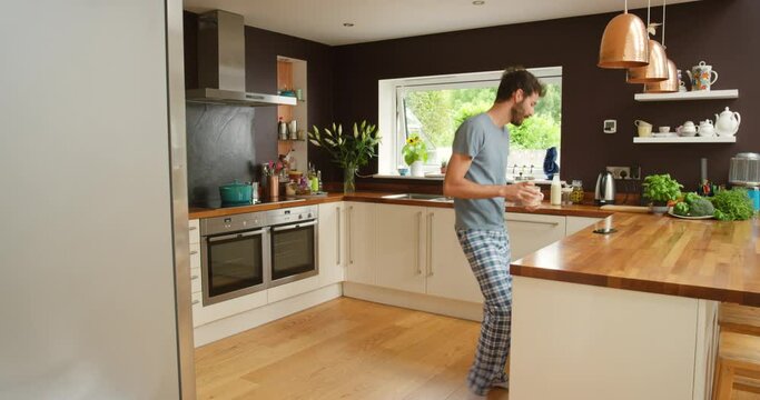 Man, dancing or home for coffee with cellphone, relax or streaming podcast on weekend in kitchen. Person, cappucino and break on mobile app for music, dancer and online radio in apartment in morning