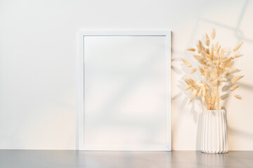 Blank picture frame and dried flower in a vase on white background