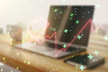 Double exposure of creative abstract heart rate hologram and modern desktop with laptop on...
