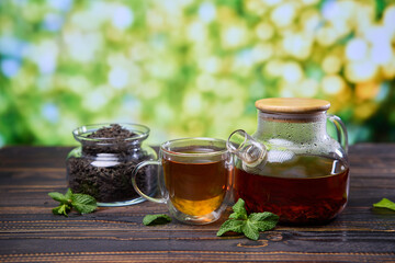 natural organic herbal tea in glass teapot and cup on a wooden table