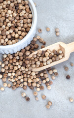 Whole white peppercorns on mottled grey surface with copy space