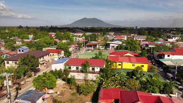 Drone flight over colorful roofs of houses in Balibago Suburb at sunny day. San Fernando City with epic Volcano in background. Philippines, Asia. Aerial birds eye shot.