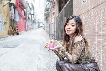 Chinese woman in her 20s eating street food in the city of Hong Kong Island...