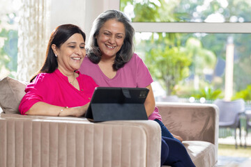 Portrait of an Elderly Woman and her Daughter Using digital tablet at Home.