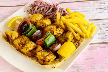 Joojeh Kabab with Skewer and shahlik with lemon, onion and french fries served in dish isolated wooden table top view of tandoori grill bbq food