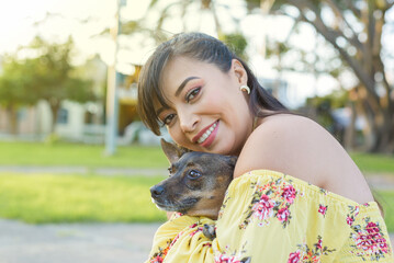 Obraz premium Woman hugging her pet in a public garden at sunset. Dog lover.