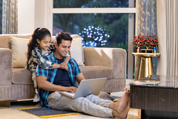 Father and daughter using laptop at home