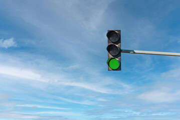 Modern traffic light with green light in front of cloudless sunny blue sky