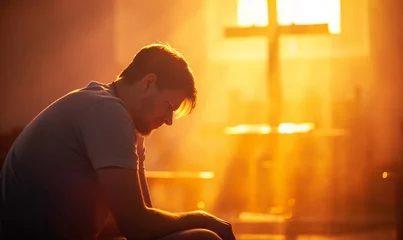 Rollo A man prays and suffers in a church against the background of a cross illuminated by the sun. Suffering and faith. Salvation of the soul. © Honey Bear