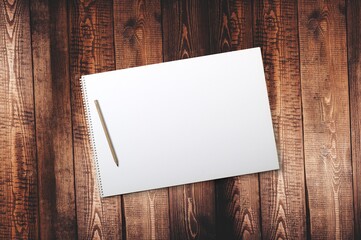 notepad on wood surface with pen overlayed photo