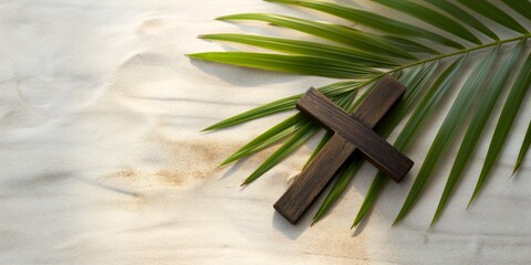 A palm branch and a wooden Christian cross lie on the sand. View from above. Palm Sunday.
