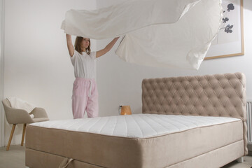 Woman changing bed linens at home in her bedroom, cozy domestic lifestyle, housewife cleaning,...