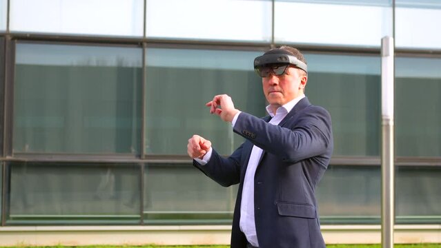 Businessman gesturing wearing augmented reality innovative goggles outdoors in a financial complex