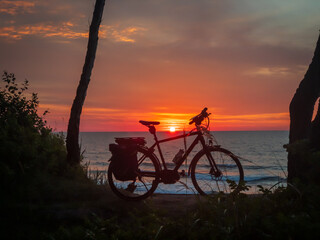 Peaceful scene with a bike silhouette against a colorful ocean sunset. Concept of leisure and...