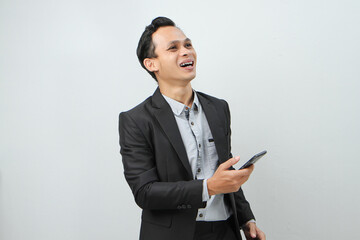 happy asian indonesian business man in suit holding smart phone on isolated background