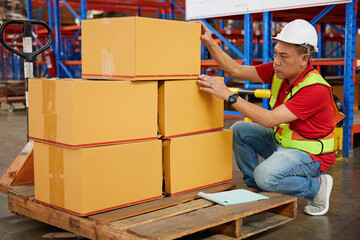 factory worker or warehouser checking corrugated boxes in the warehouse storage - obrazy, fototapety, plakaty