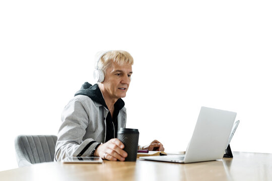 An older dude is using a laptop to browse the web with his earphones. A clear background.
