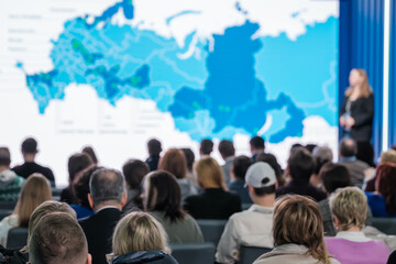 Focused shot of a business presentation to a diverse audience with a world map projection. - obrazy, fototapety, plakaty