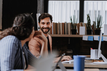 Two freelancers talking while working in shared work area. Concept of coworking, common workspaces for business, startups.